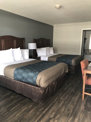 A hotel room with two beds, a desk, and a chair.
