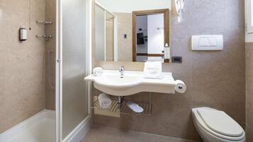 Et moderne badeværelse med en glasafskærmet brusekabine, en vask med håndklæderadiator og et toilet.