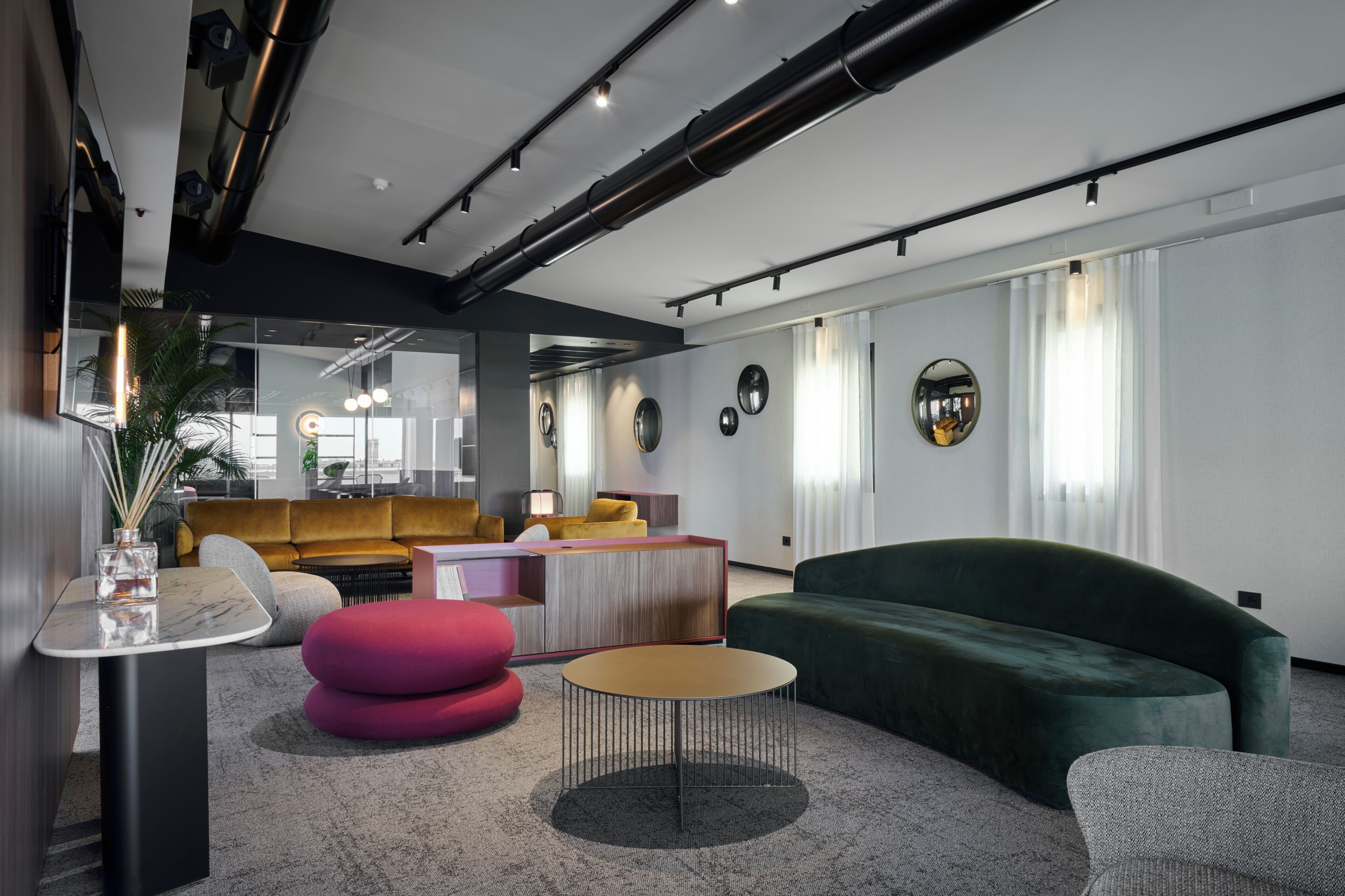 A modern interior with a green sofa, a pink ottoman, and a round coffee table.