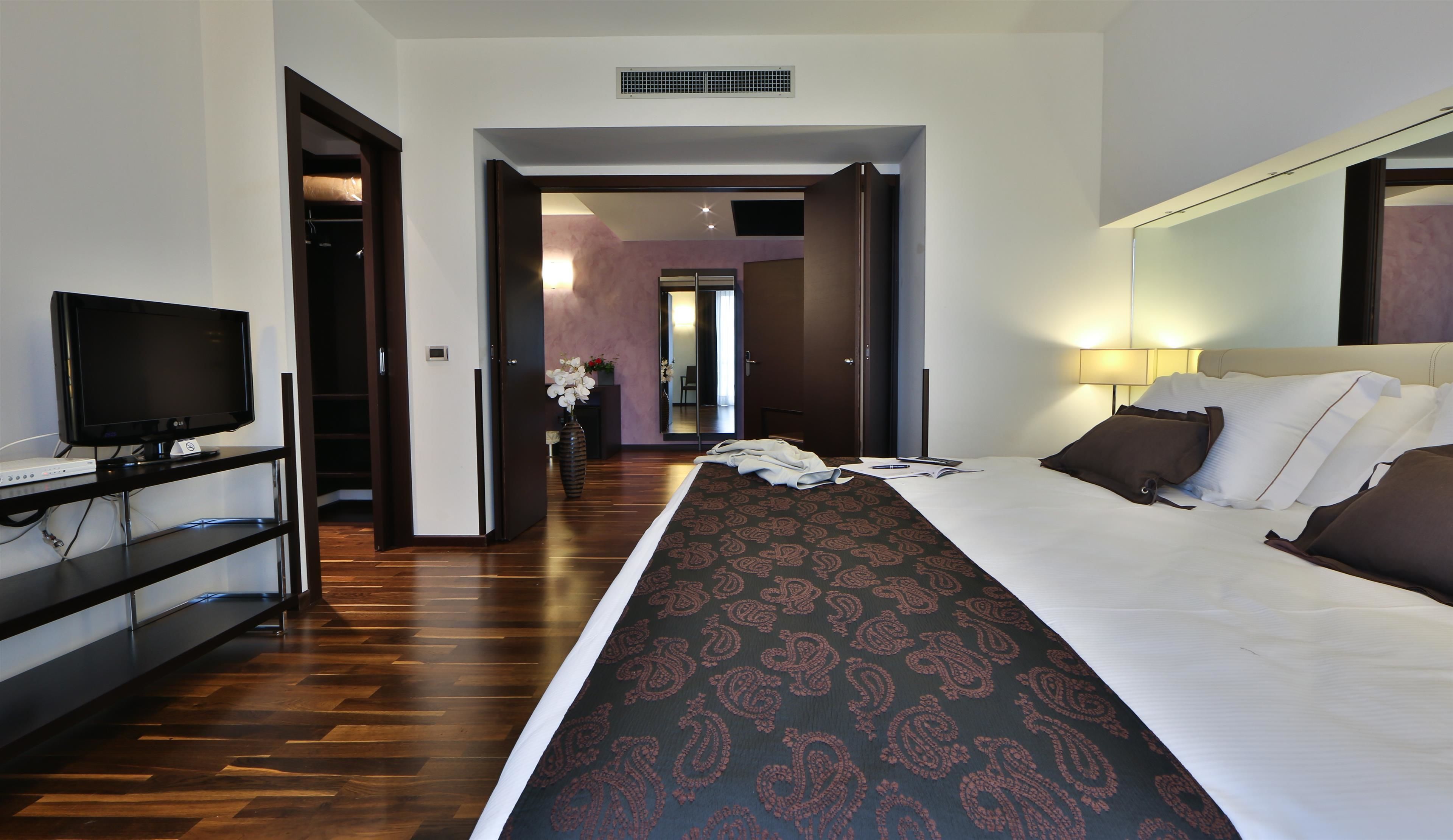 A hotel room with a bed, a TV, a desk, and a mirror.