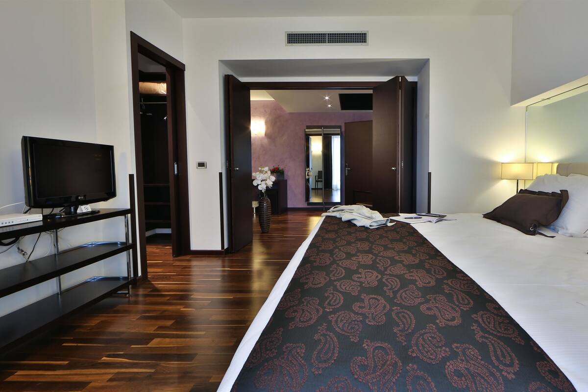 Une chambre d’hôtel avec un lit, une télévision, un bureau et un miroir.