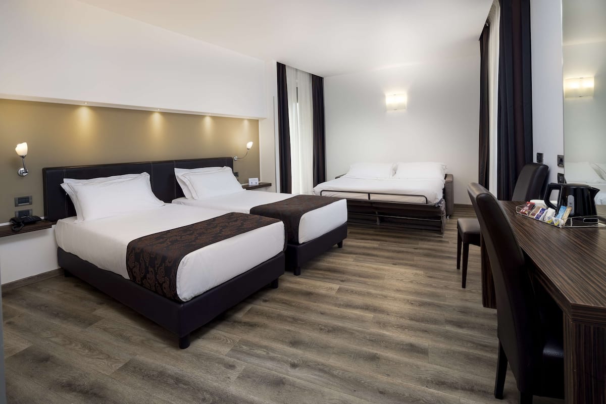 Une chambre d’hôtel avec deux lits, un bureau et une chaise.