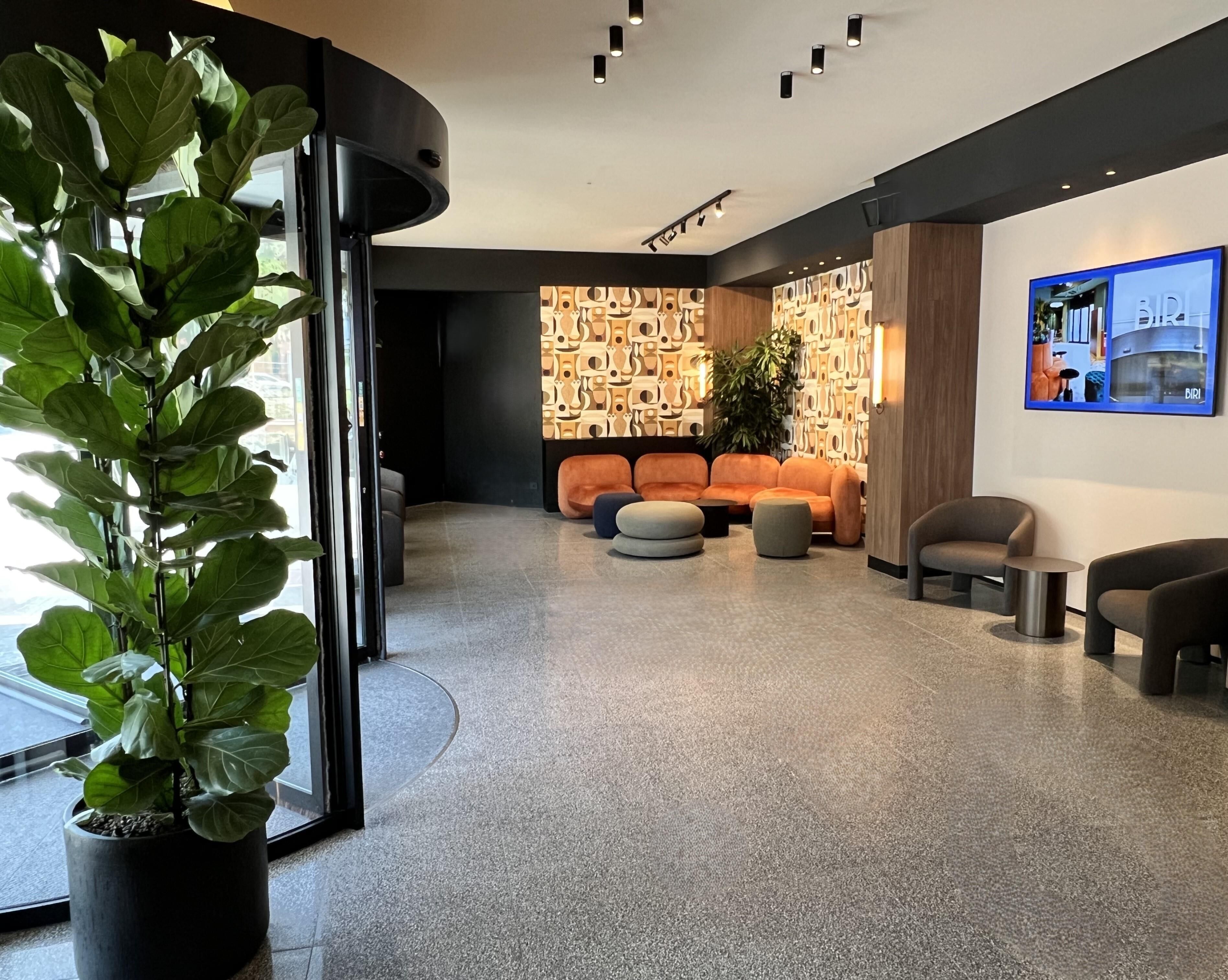 A modern interior with a seating area, a large potted plant, and a wall-mounted TV.