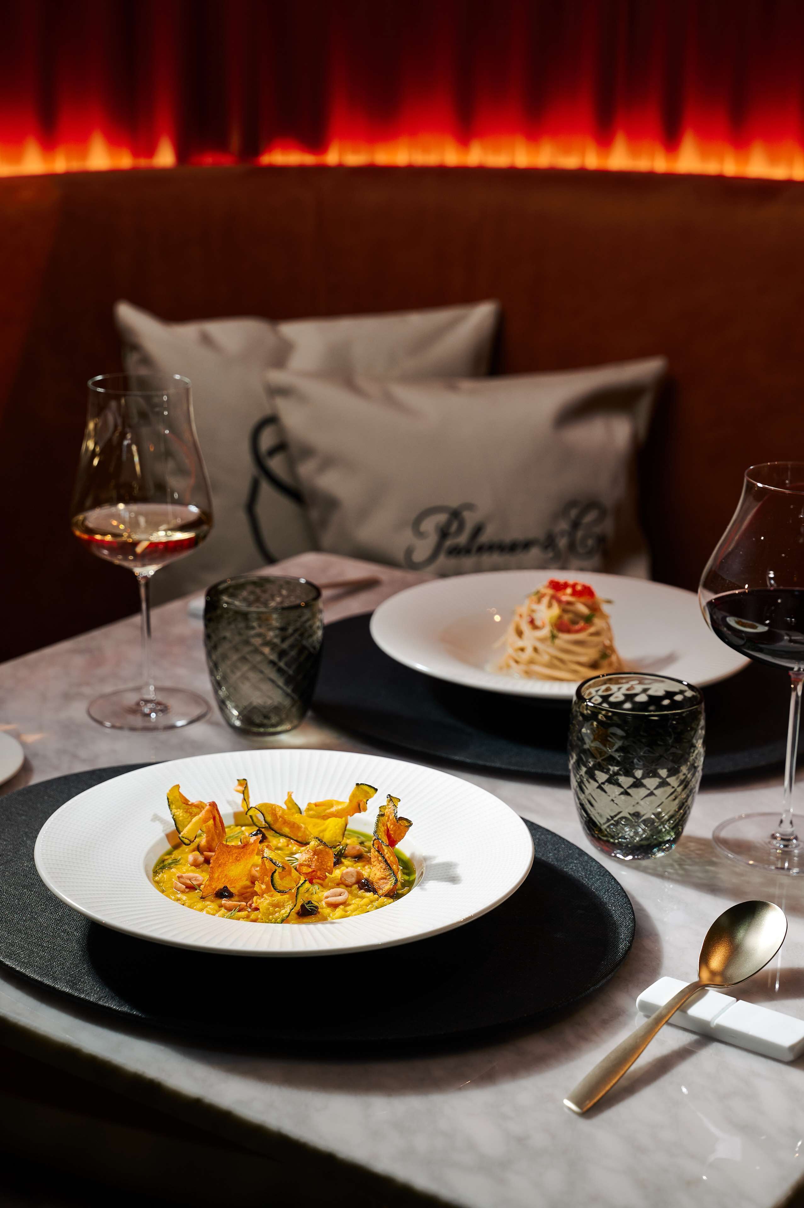 Une table à manger avec des assiettes remplies de nourriture, des verres de vin et une bougie.