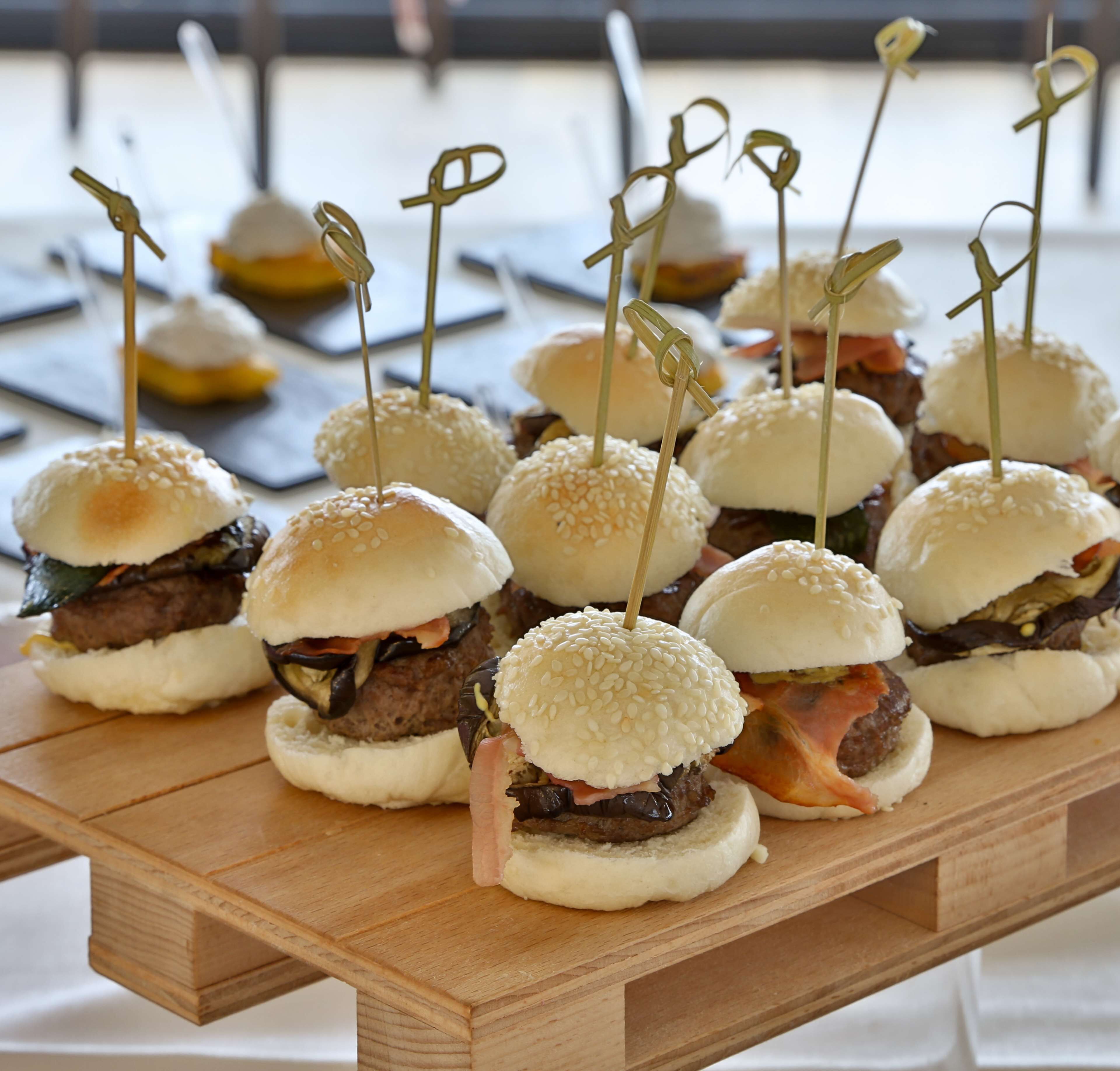 A wooden table with several mini sandwiches, each held together by toothpicks.