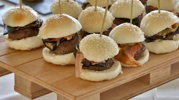 A wooden table with several mini sandwiches, each held together by toothpicks.