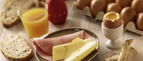 Desayuno con pan, huevos, queso y un vaso de jugo de naranja.