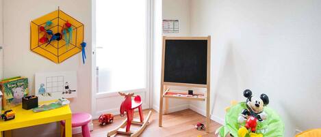 A child's playroom with a desk, chair, rocking horse, and various toys.
