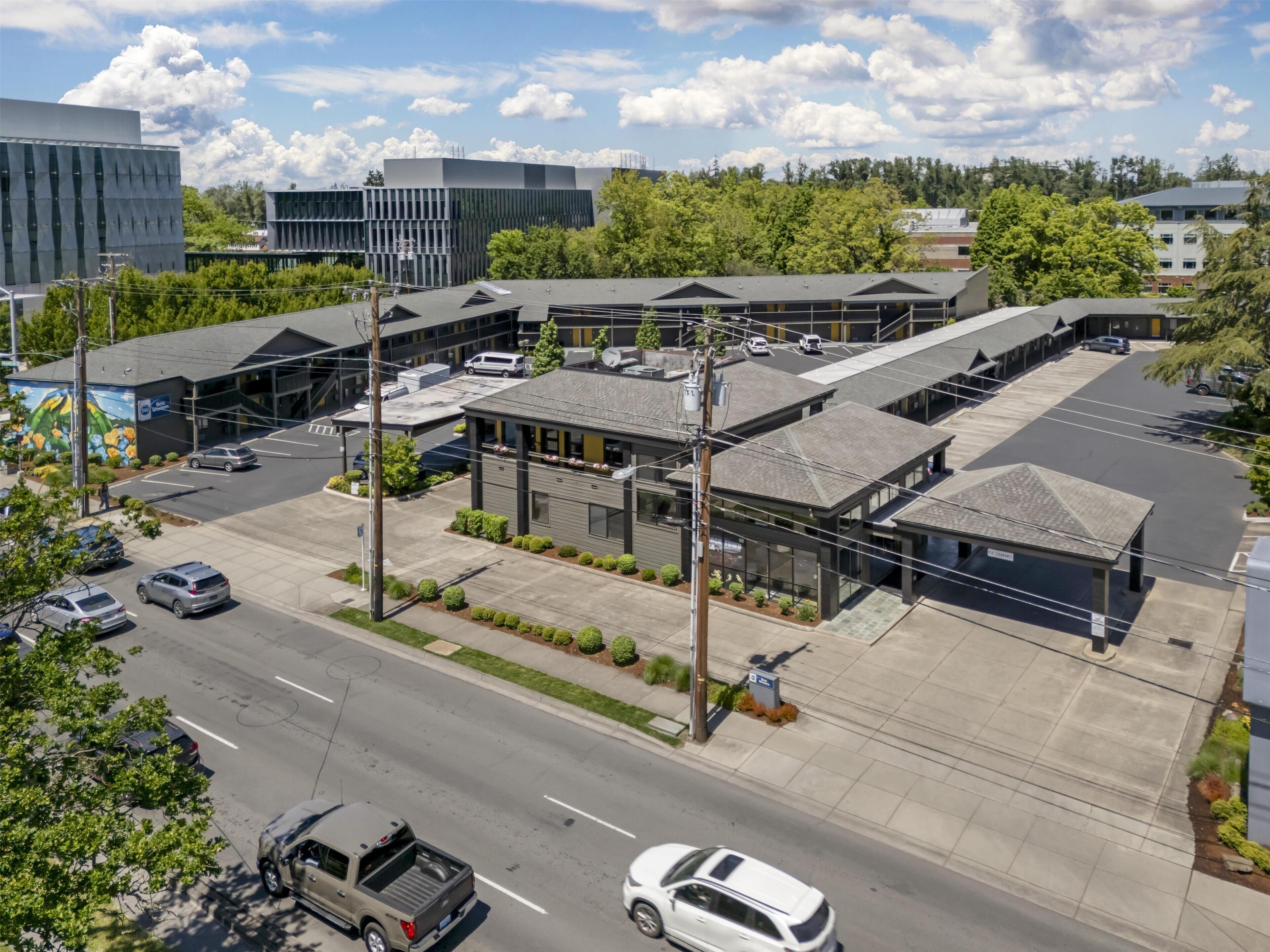 A commercial building with multiple parking spaces, a road in front, and a mural on the side.
