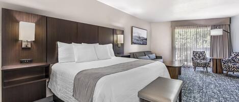 A hotel room with a large bed, bedside tables, a desk, and a chair.
