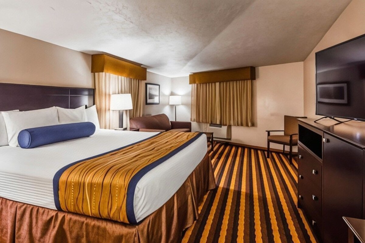 Une chambre d’hôtel avec un grand lit, une télévision, un bureau et une chaise.