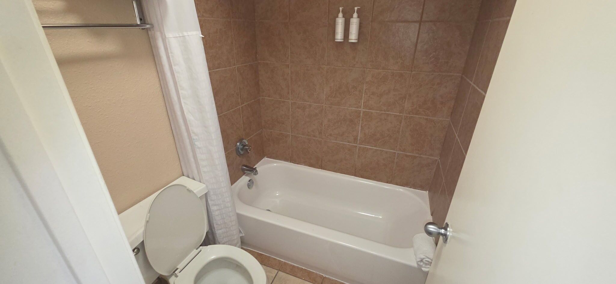 A bathroom with a toilet, a bathtub, and a shower curtain.