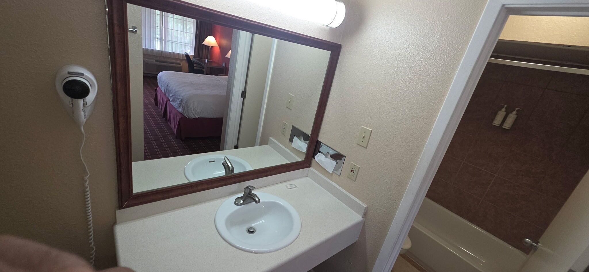 Un baño de hotel con lavamanos, espejo y zona de ducha.
