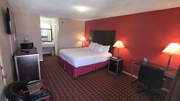 A hotel room with a bed, two bedside tables with lamps, a desk with a chair, and a television on the wall.
