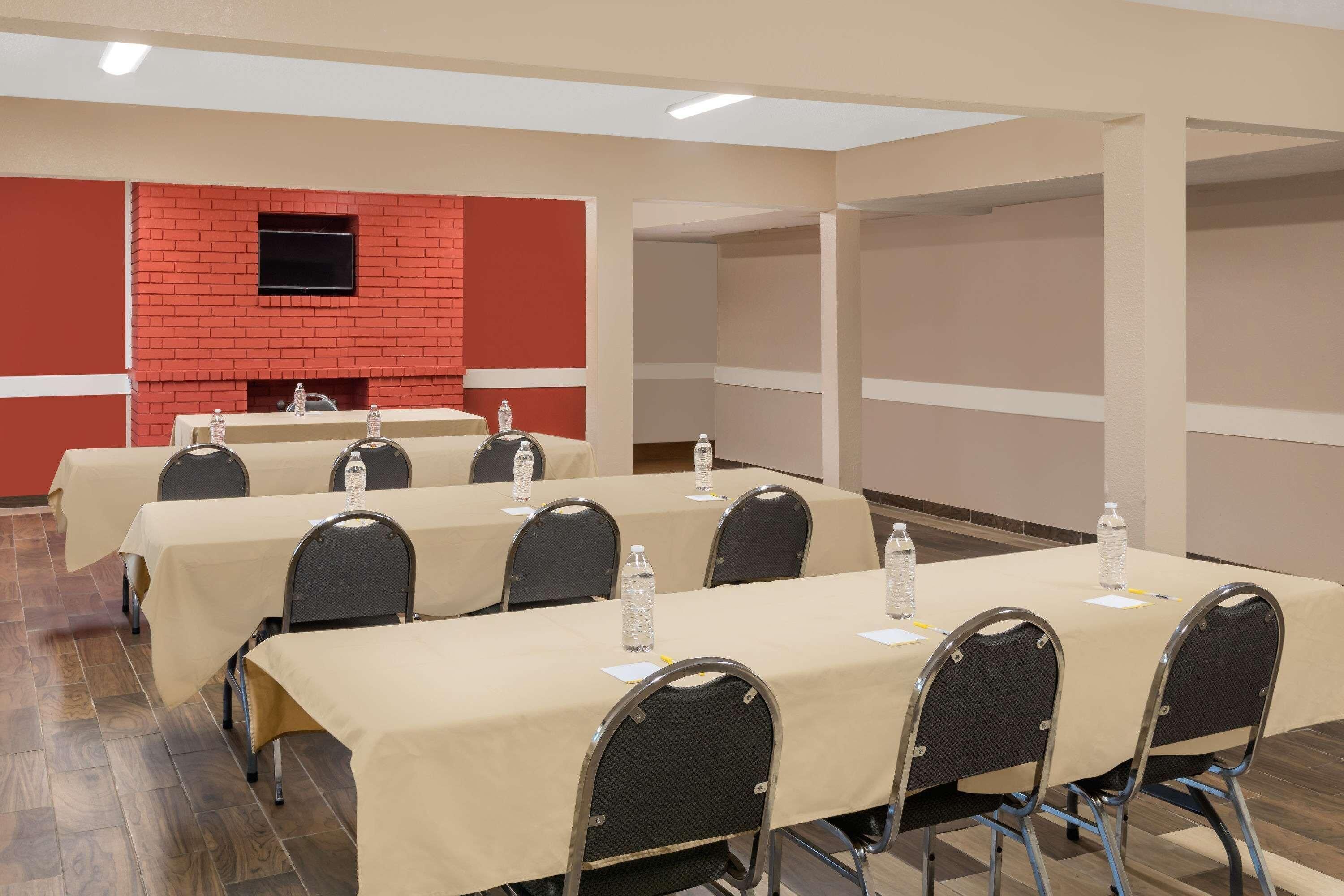 A conference room with tables, chairs, and a red brick wall.