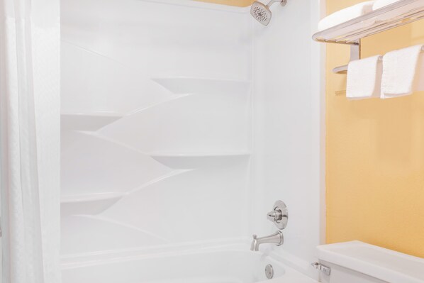 A bathroom with a bathtub, a showerhead, and a towel rack with towels.