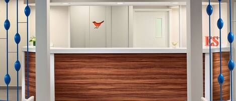 Ein moderner Empfangsbereich mit einer Wand aus Holzpaneelen, einer roten Vogeldekoration und blauen, hängenden Elementen.