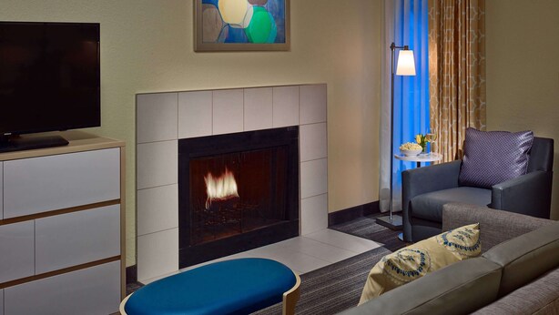 A living room with a flat-screen TV, a fireplace, a sofa, and a painting on the wall.