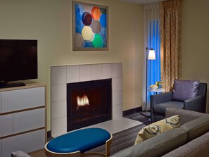Una sala de estar con televisión de pantalla plana, chimenea, sofá y un cuadro en la pared.
