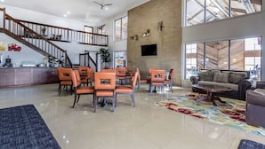 Un vaste espace de vie doté d’un haut plafond, d’un escalier et d’un coin repas avec des chaises orange.