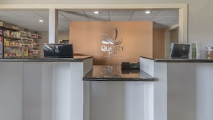 Un comptoir d’accueil avec une enseigne indiquant « Quality Inn By Choice Hotels ».