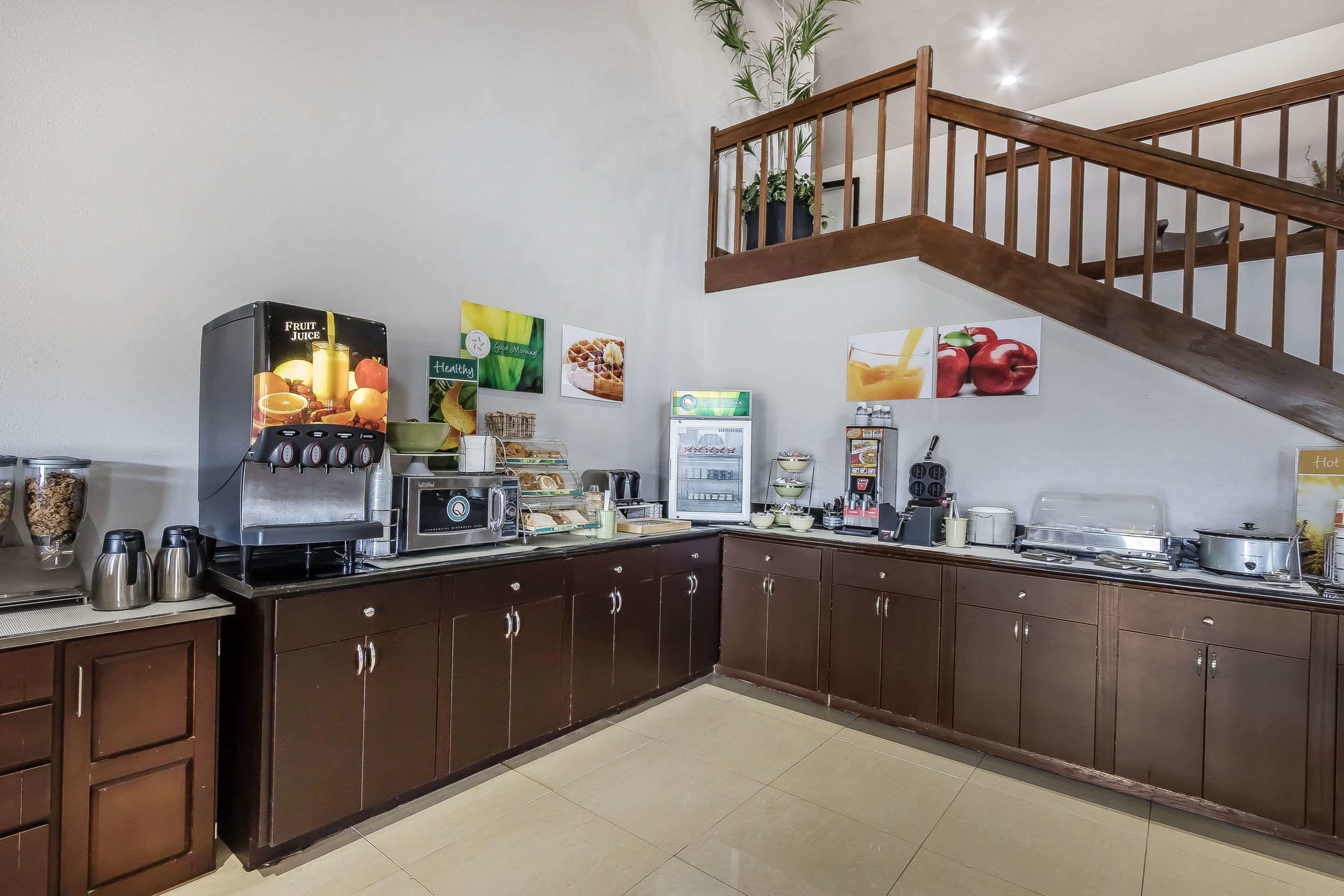 Una cocina con dispensador de jugo de frutas, cafetera y diversos alimentos sobre la encimera.