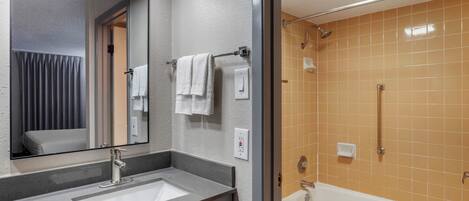A bathroom with a sink, mirror, towel rack, and a bathtub.