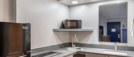 A modern kitchen with a stainless steel refrigerator, a microwave, a sink, and a countertop.