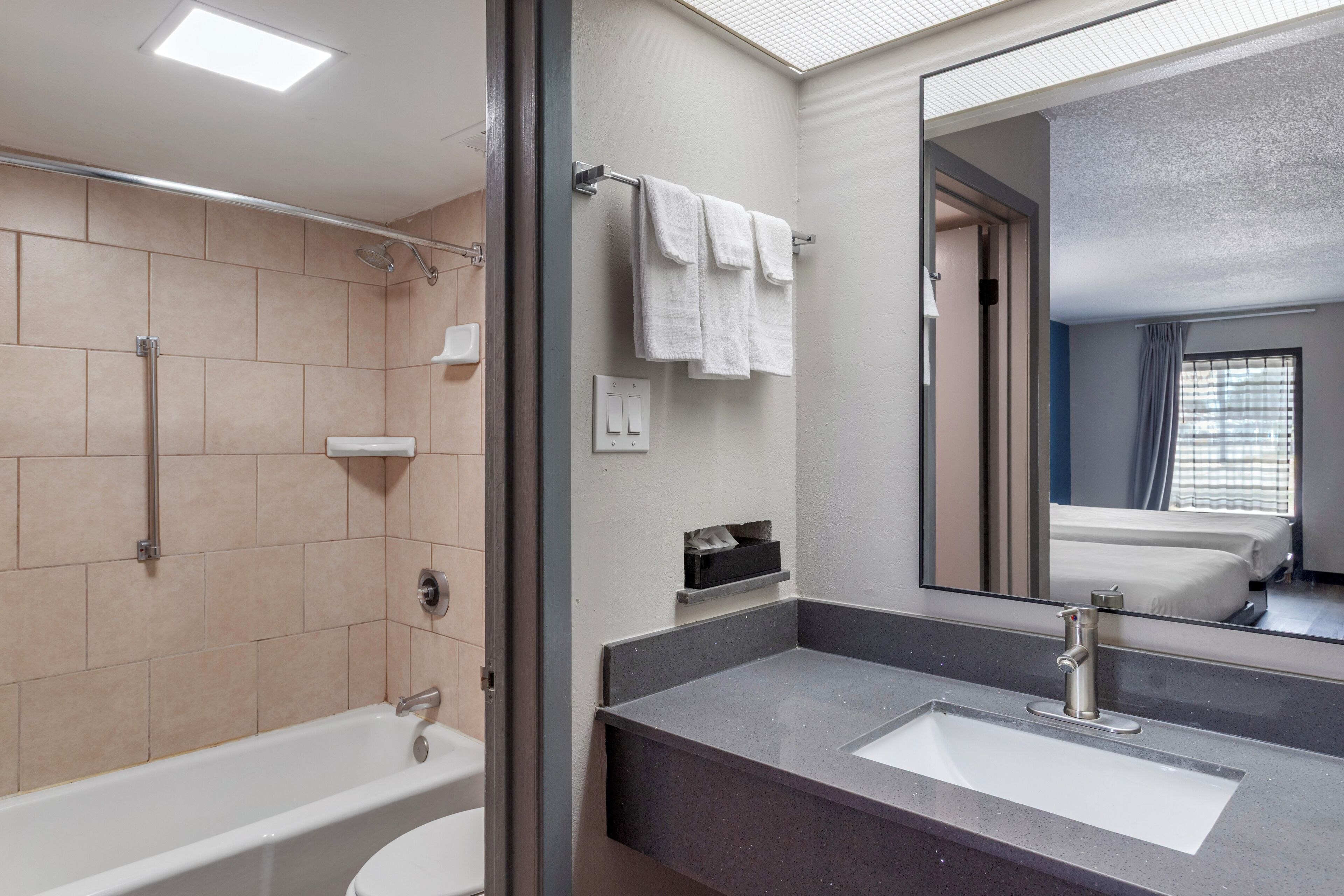 A modern bathroom with a bathtub, a sink, and a large mirror.