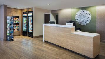 Ein Hotel-Rezeptionsbereich mit einem Holzbüro, einer Wanddekoration und Verkaufsautomaten.