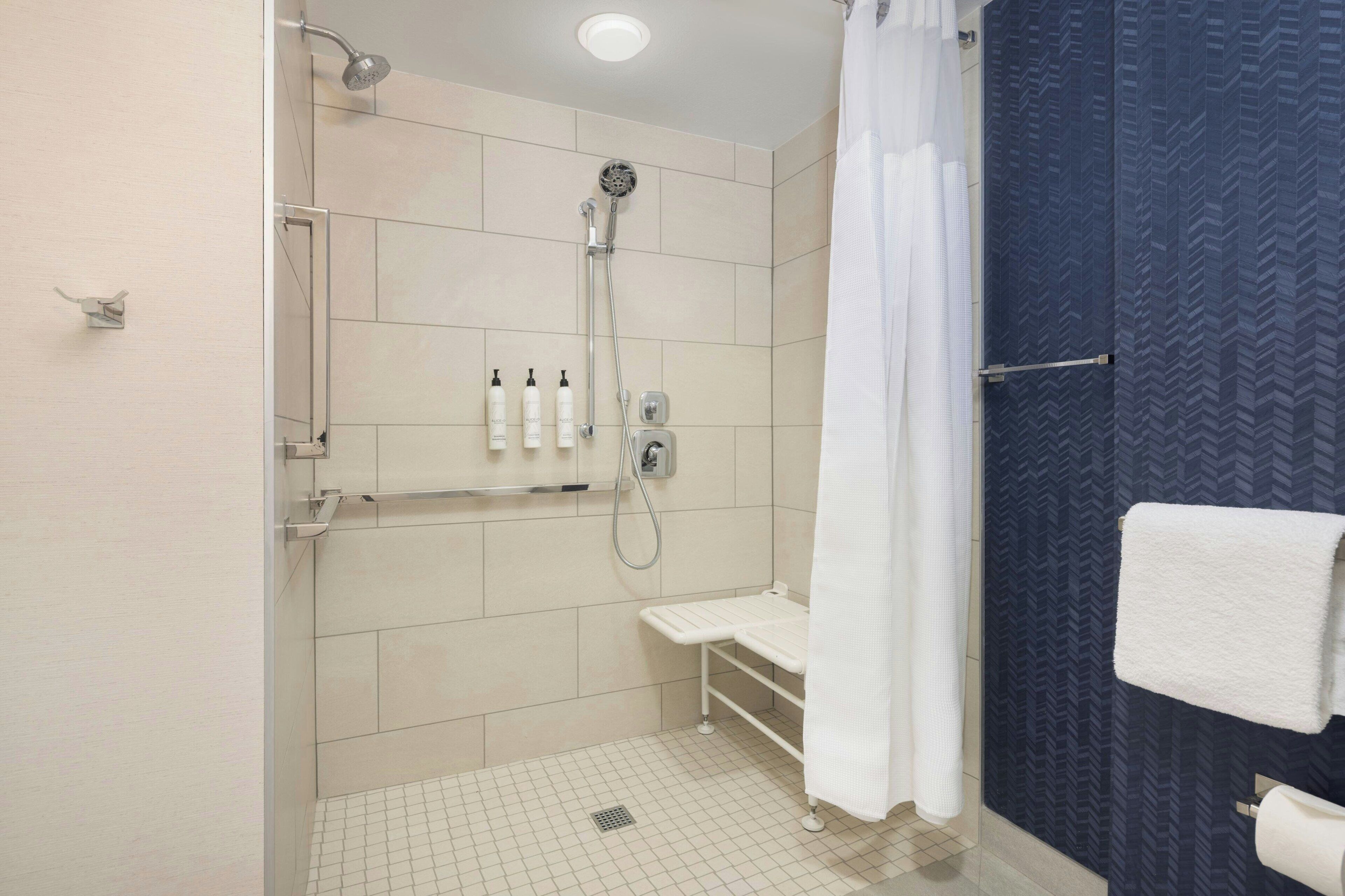 A modern bathroom with a shower, a toilet, and a towel rack.