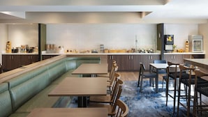 Una cocina moderna con una encimera larga, electrodomésticos integrados y una zona de estar con mesas y sillas.