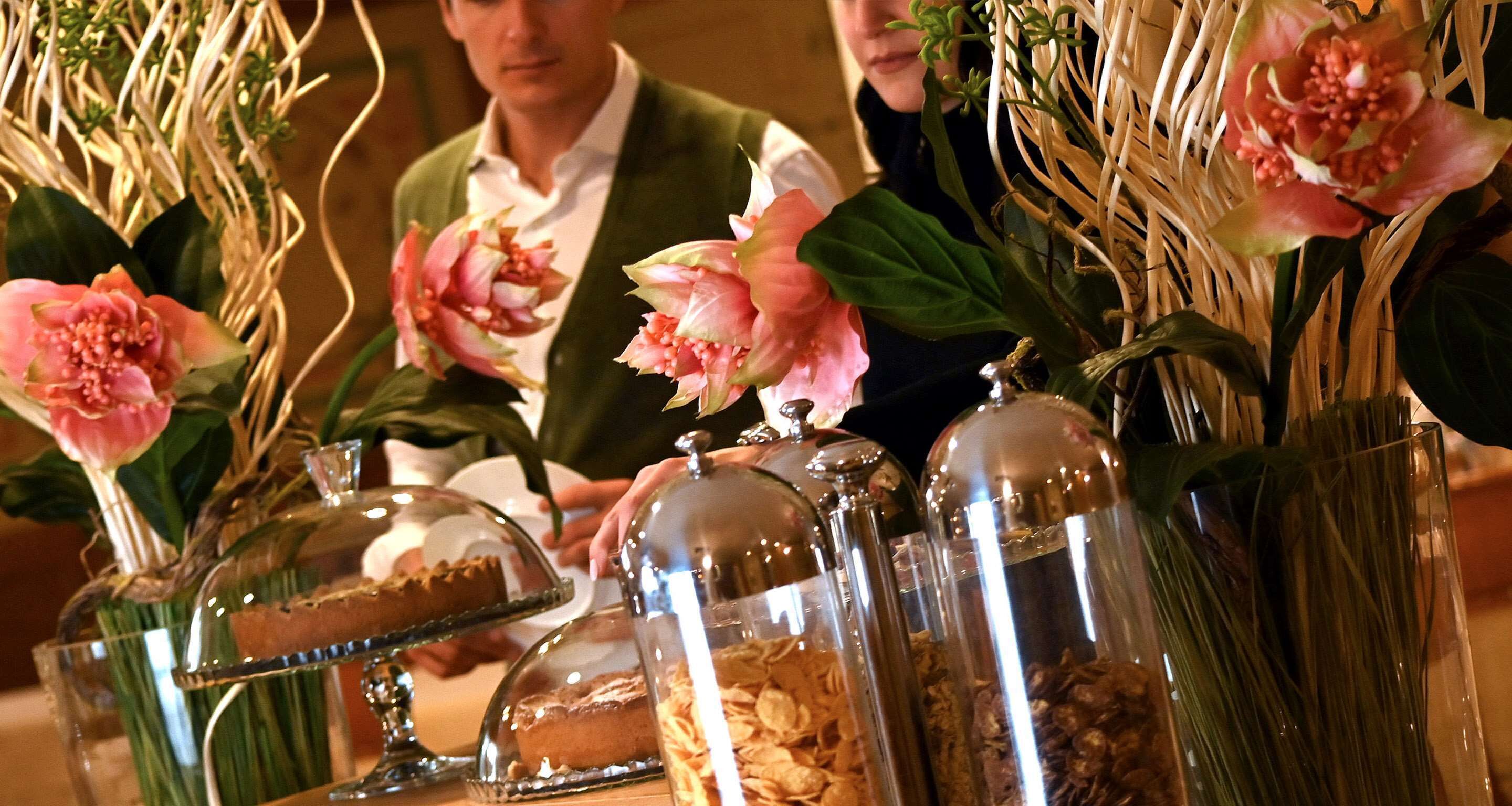 Una mesa con campanas de cristal, un jarrón con plantas secas y un pastel.