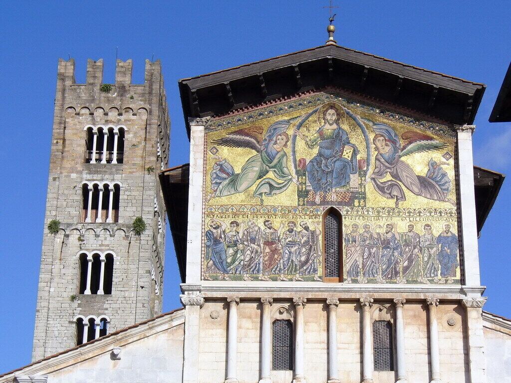 A historic building with a tall tower and a detailed mosaic on the facade.