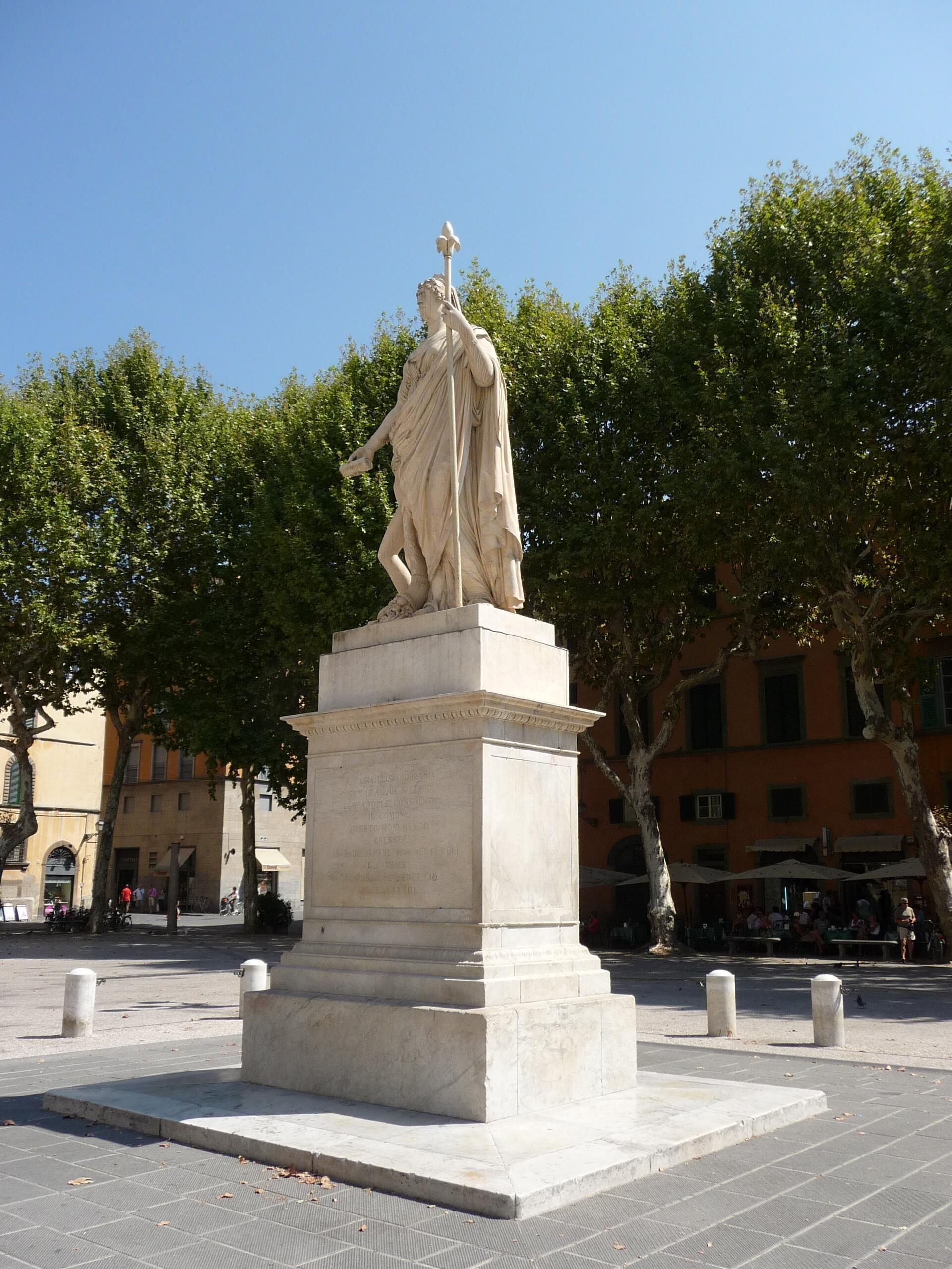 Eine Marmorstatue einer Frau auf einem Sockel in einem öffentlichen Platz.