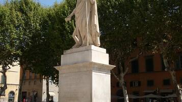 A marble statue of a woman on a pedestal in a public square.
