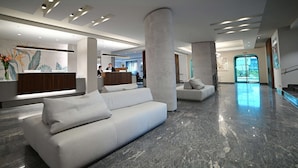 A modern lobby with a reception desk, two sofas, and a large pillar.