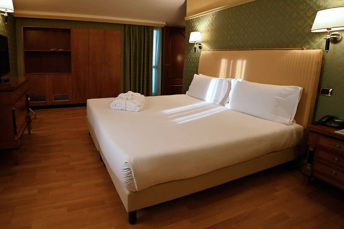 Una habitación de hotel con una cama grande, un escritorio con lámpara y un armario.