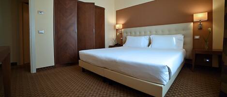 A hotel room with a large bed, a wardrobe, a bedside table, and a nightstand.