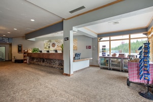 A hotel reception area with a check-in counter, a directory sign, a plant, and a snack cart.