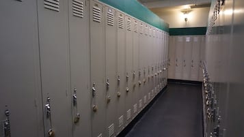 A row of lockers with combination locks, a tiled floor, and a light fixture on the ceiling.