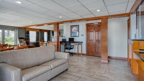 A hotel lobby with a sofa, wooden furniture, a desk, and a framed picture on the wall. - SureStay Hotel by Best Western Bowling Green North (Bowling Green)