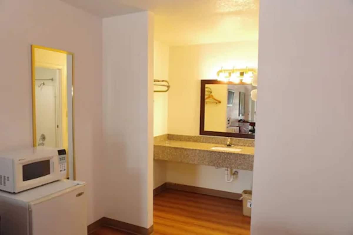 A compact bathroom with a microwave, a sink, and a mirror with lights.