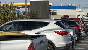 Un estacionamiento con varios coches, el cartel de USA Inn y un edificio con tejado azul y verde.