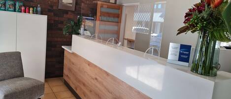 A reception area with a wooden counter, a framed picture on the wall, and a sign about service promise.