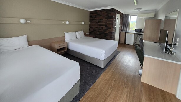Une chambre d’hôtel avec deux lits, un bureau avec un ordinateur, une petite kitchenette et une salle de bain.