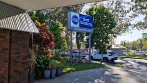 Une enseigne Best Western avec le logo de Parkside Motor Inn, entourée de plantes en pot et de voitures garées.