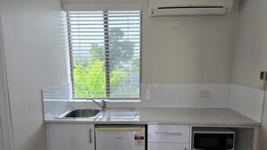 Une cuisine de taille réduite, dotée d’une fenêtre, d’un four à micro-ondes encastré et d’un réfrigérateur.