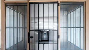 A room with a barred door and windows, a small trash bin, and a light switch on the wall. - OYO Hotel Oklahoma City South I-35 and SE 29th (Oklahoma City)