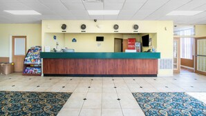 A reception area with a wooden reception desk, multiple clocks, a bulletin board, and a small display of magazines. - OYO Hotel Oklahoma City South I-35 and SE 29th (Oklahoma City)